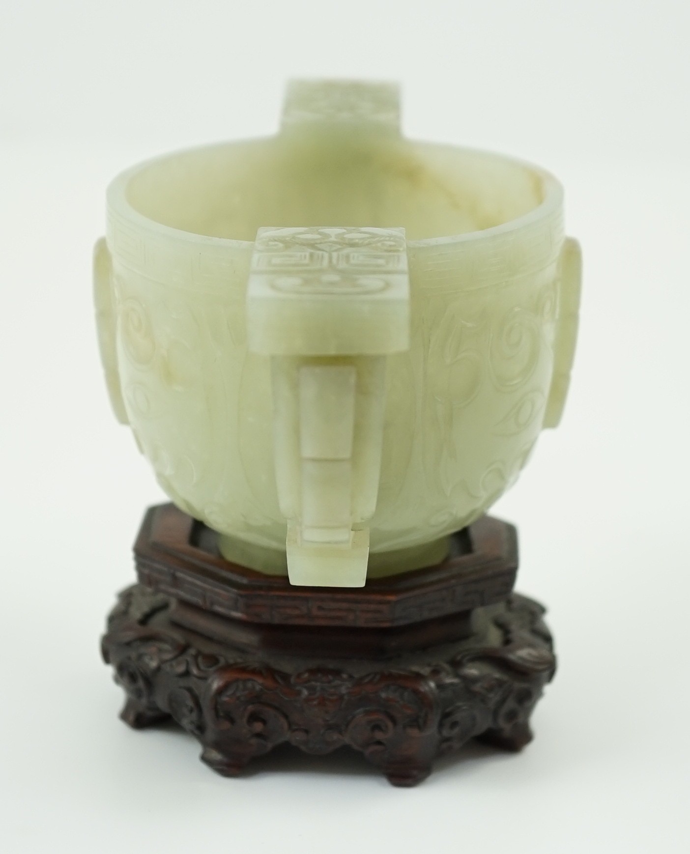 A Chinese archaistic celadon jade two handled cup, 17th century, 12.9cm across 6.1cm high, associated wood stand